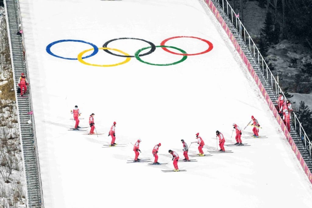 Shot from above of ski slope with Winter Olympics logo and skiers.