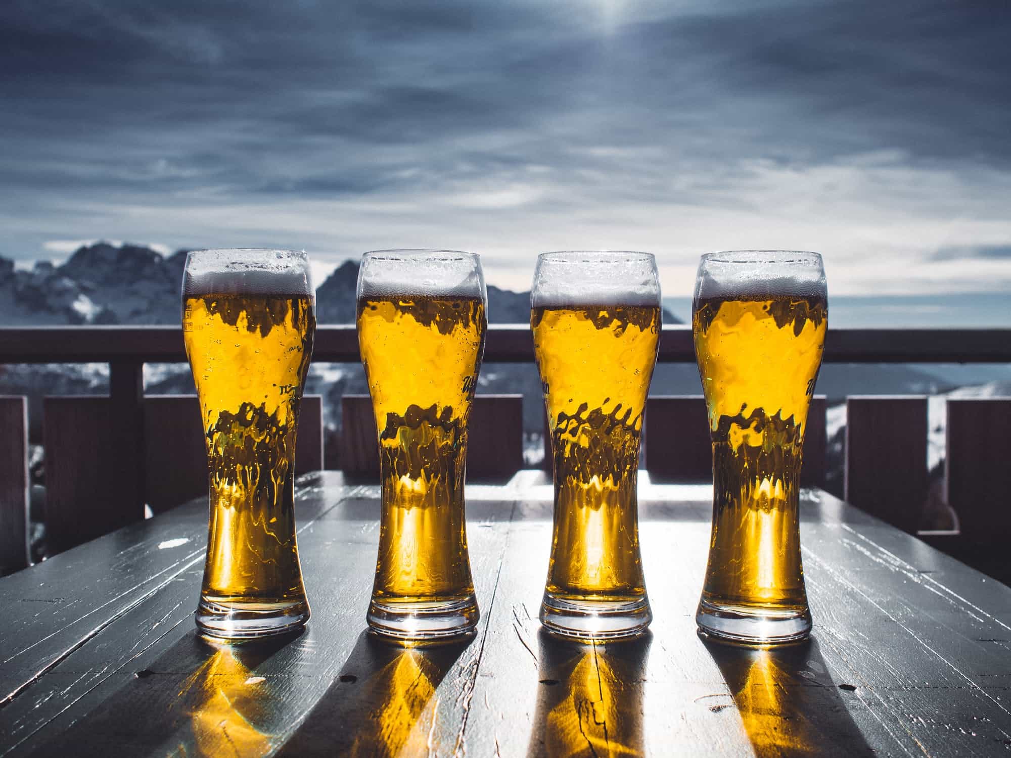 Beers lined up on a table with mountains behind