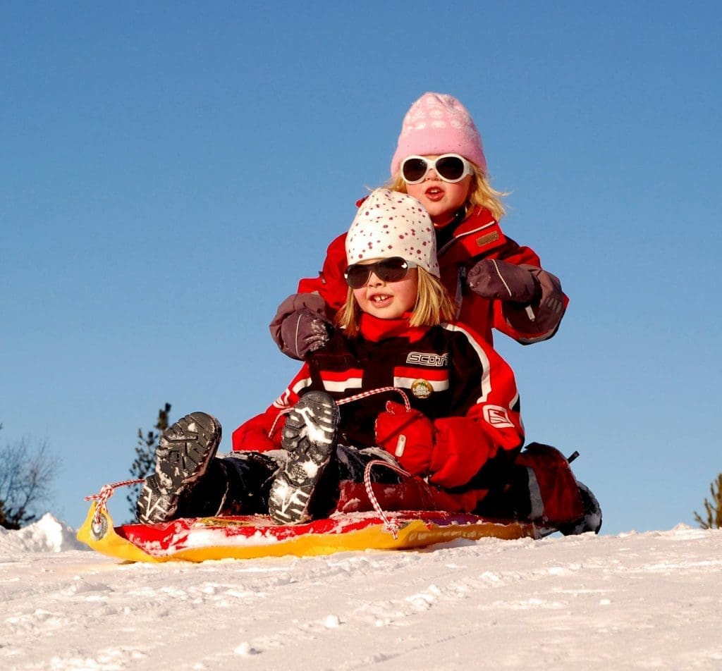 Skiing with kids - children sledding in the Alps